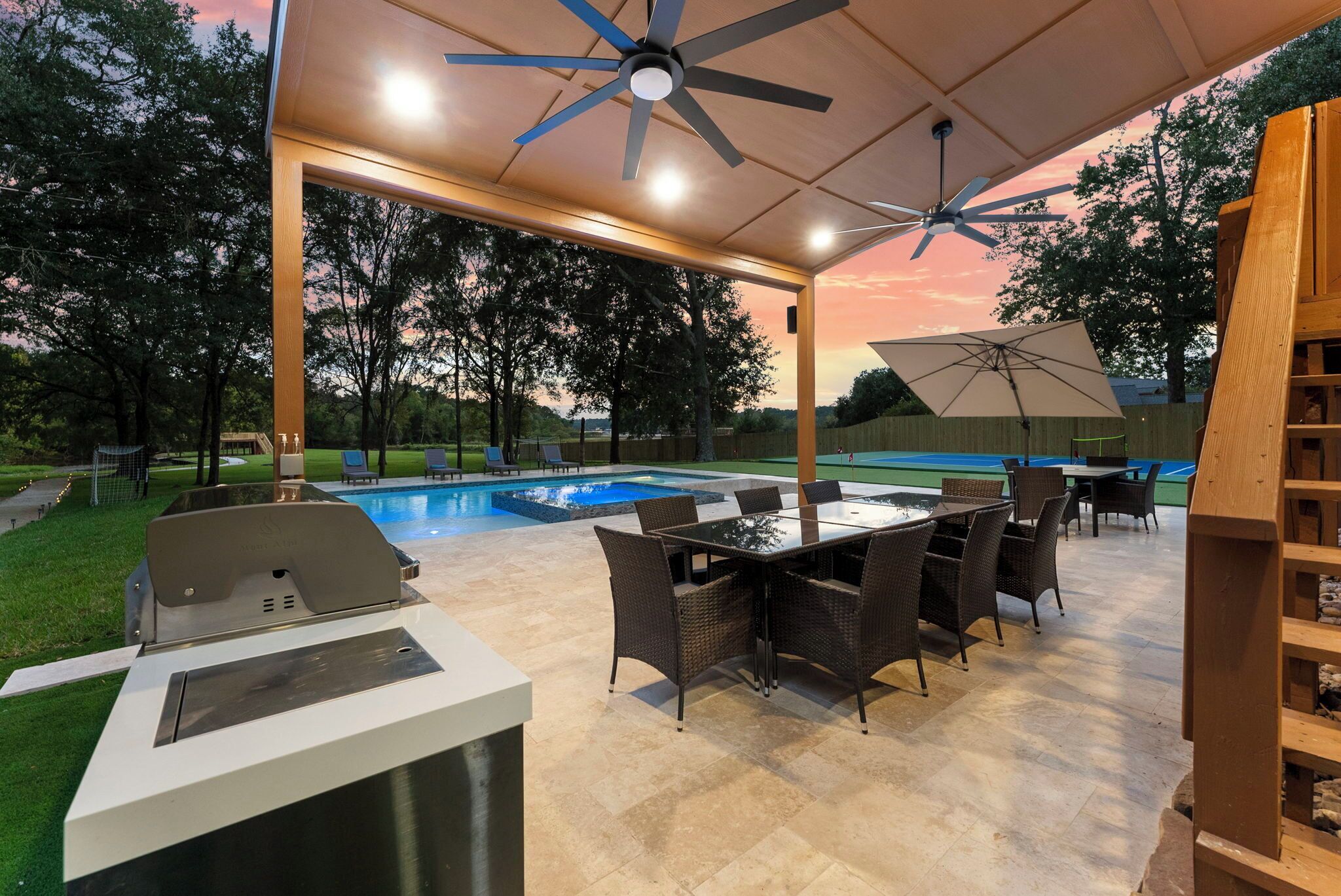 An outdoor patio with a pool, a grill, and a table with chairs.