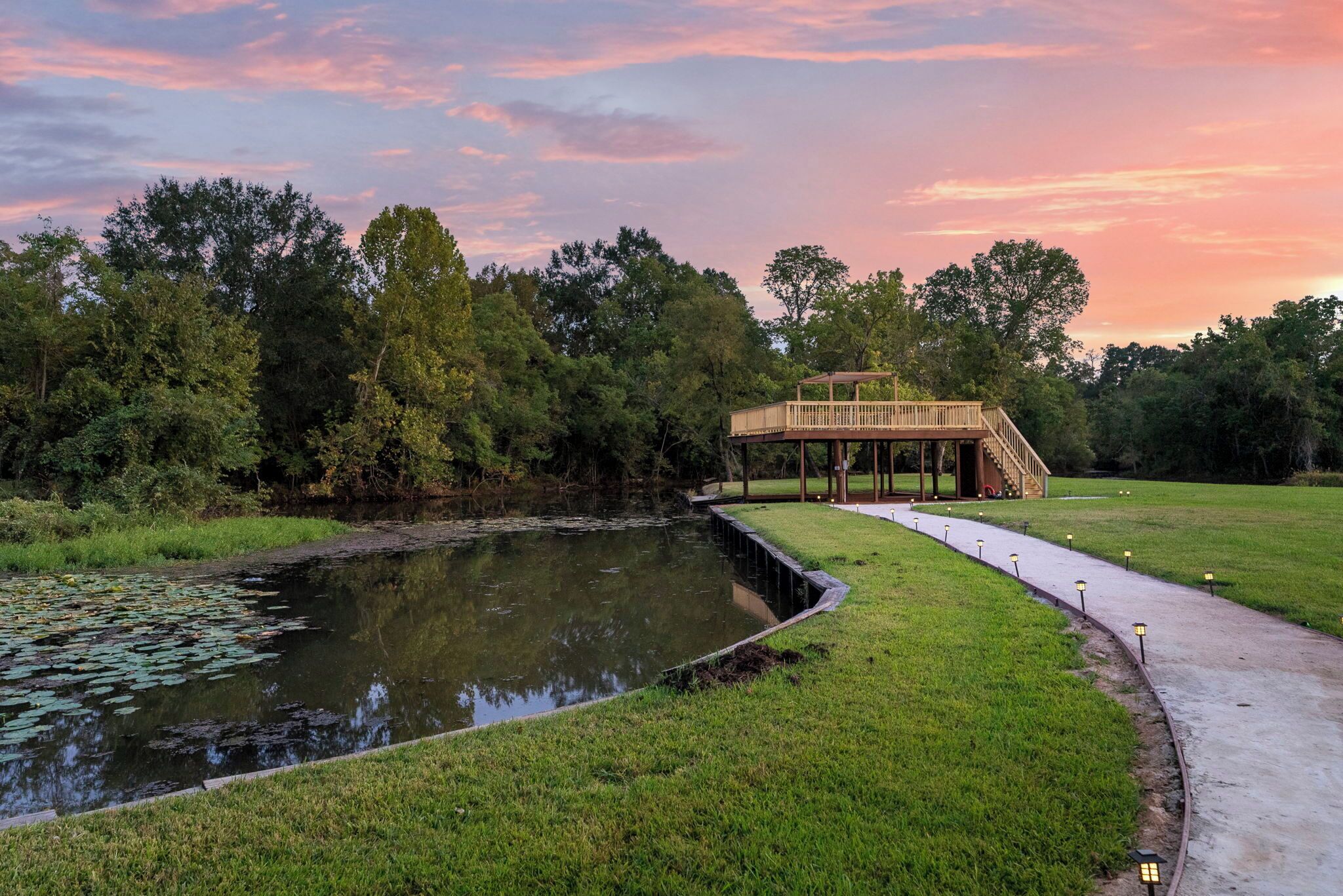 A serene park with a pond, a wooden gazebo, and a walking path.