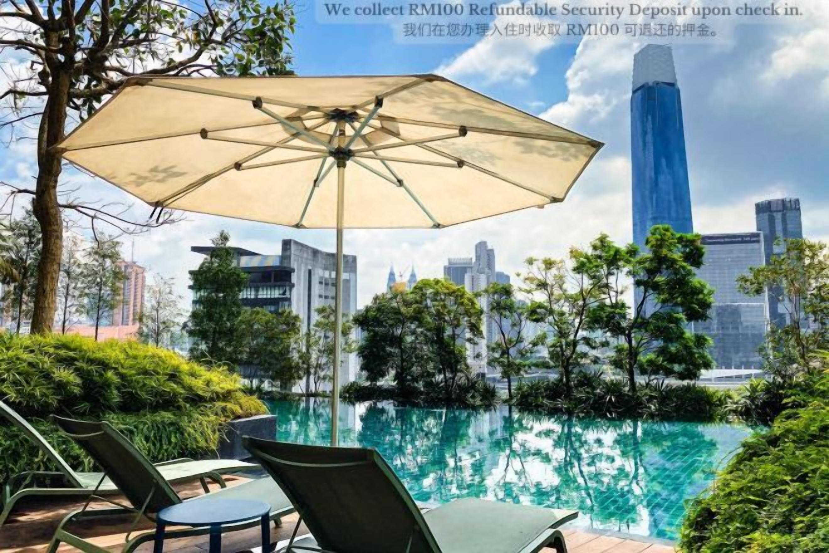 A poolside area with chairs and an umbrella, overlooking a city skyline.
