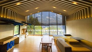 A modern interior with a large window, a wooden table, and a sofa area. - Continew Residence by Janice's Homestay (Kuala Lumpur)