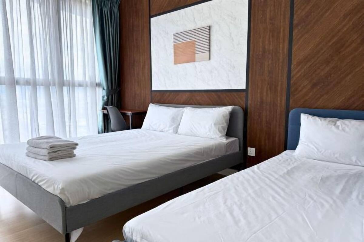 A hotel room with two beds, a wooden panel wall, a marble artwork, and a window with sheer curtains.