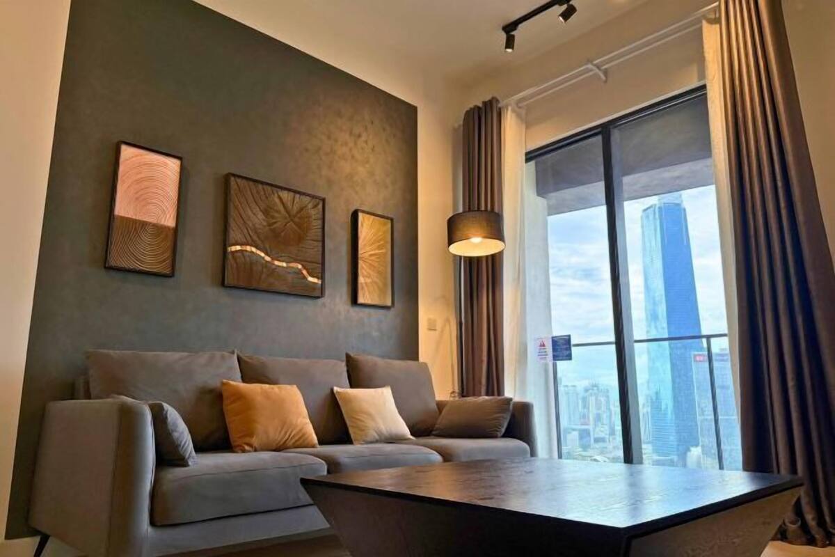 A modern living room with a grey sofa, a coffee table, and artwork on the wall.