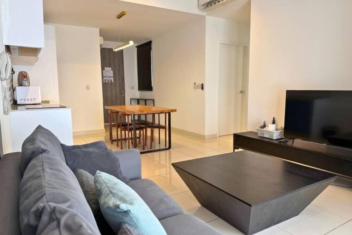 A modern living room with a sofa, a coffee table, a TV, and a dining area with a table and chairs.