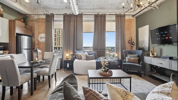 Una sala de estar moderna con comedor, sofá, televisor y vistas a la ciudad.