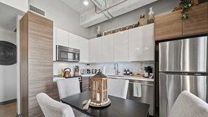 Una cocina moderna con armarios blancos, electrodomésticos de acero inoxidable y una mesa de comedor con sillas.