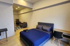 A modern bedroom with a large bed, a desk, and a chair.