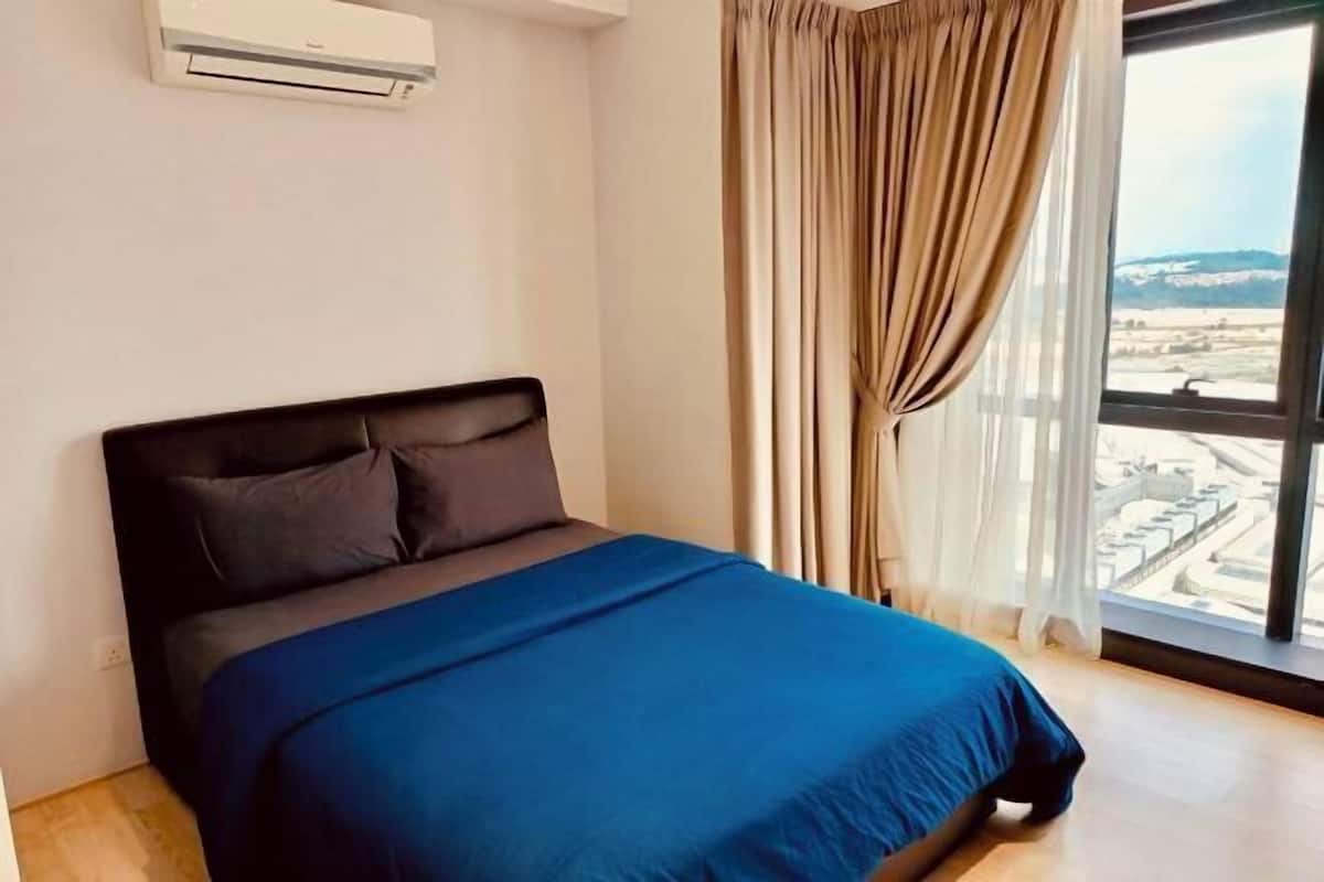A bedroom with a bed, a window with curtains, and an air conditioning unit on the wall.