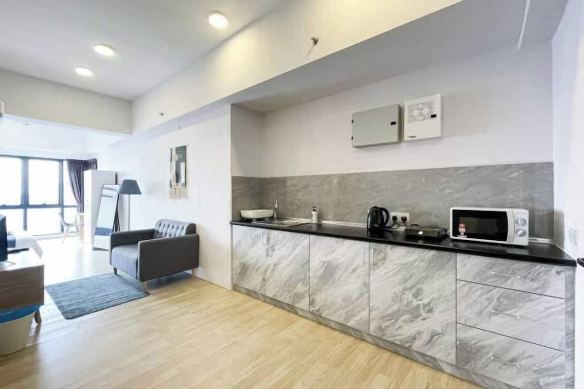 A modern kitchen with a marble countertop, a microwave, and a coffee maker.