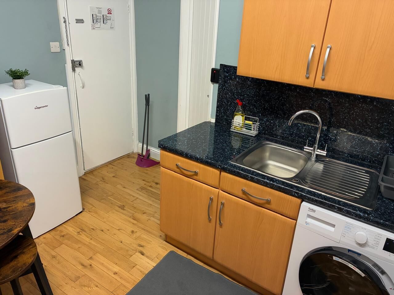 Una cocina compacta con un lavamanos, lavadora y armarios de madera.