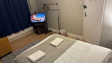 Una habitación de hotel con una cama, un televisor sobre un mueble, un armario y una lámpara de pie.