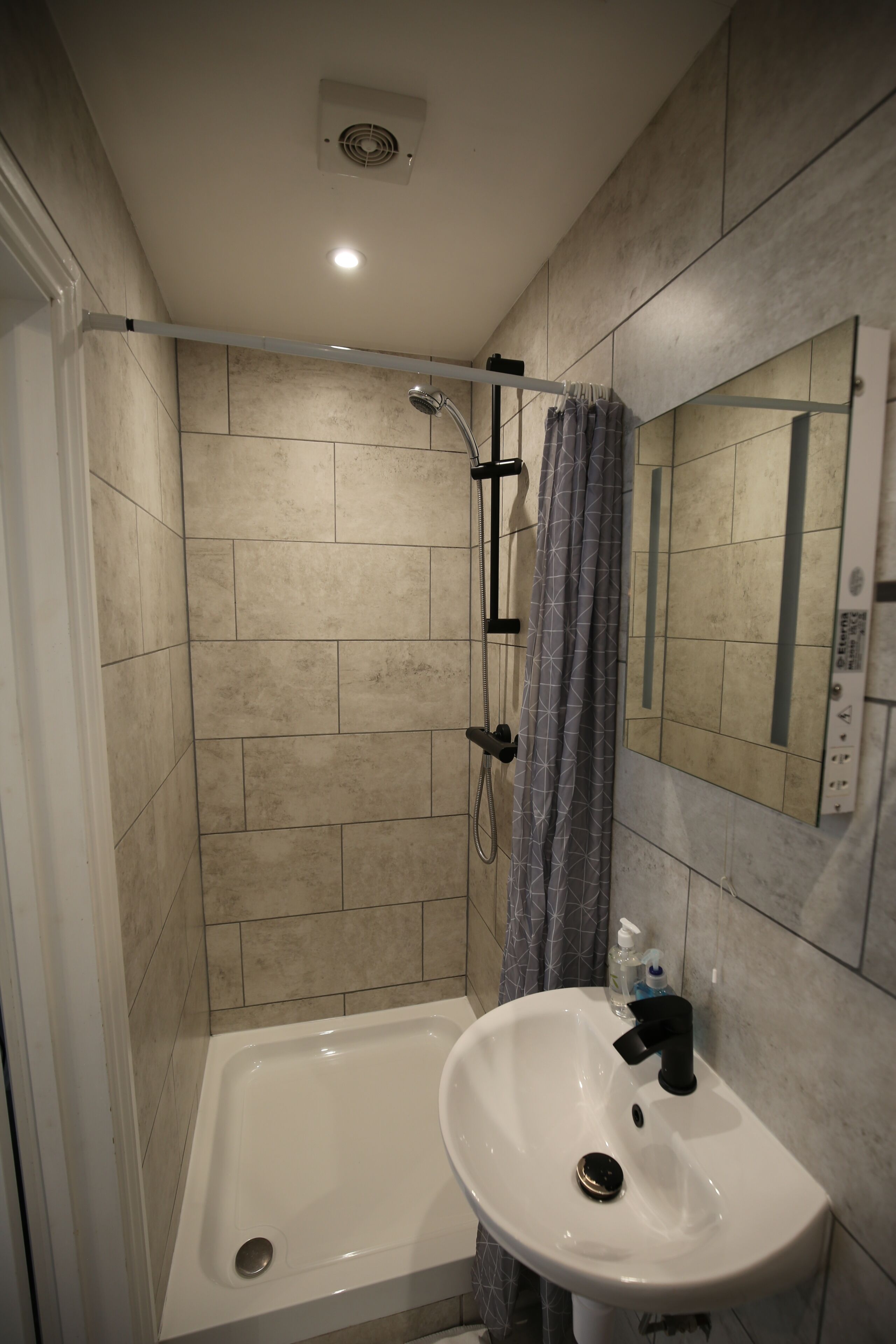 A bathroom with a shower, a sink, and a mirror.