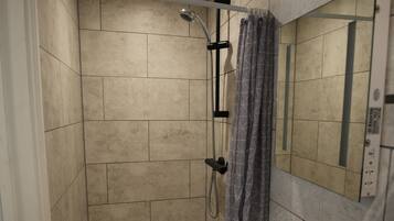 A bathroom with a shower, a sink, and a mirror.