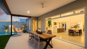 Ein modernes Haus mit Essbereich, Küche und einer Hängematte an einem Pool.