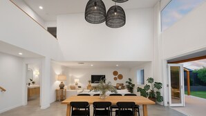 Ein moderner Essbereich mit einem Holztisch und schwarzen Stühlen, im Hintergrund eine Küche und ein großes Fenster mit Blick ins Freie.