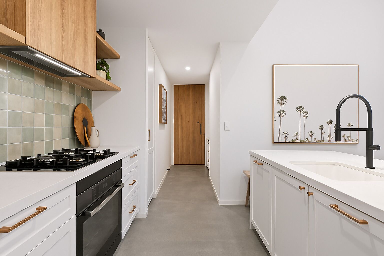 A modern kitchen with white cabinetry, a black stove, and a wooden door in the background.