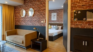 Una habitación moderna con pared de ladrillo, un sofá, una cama y una mesita de noche con lámpara.
