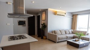 Una sala moderna con sofá, una mesita de centro y una zona de cocina con estufa.