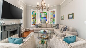 Ein Wohnzimmer mit Ecksofa, Glastisch, Kamin und großem Flachbildfernseher.