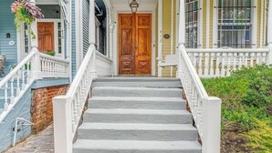 Ein zweistöckiges Haus mit Veranda, einer Holztür und einem Ziegelweg, der zum Eingang führt.