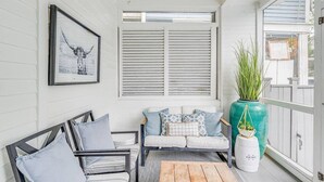 Eine gemütliche Veranda mit einer hölzernen Bank, einer gepolsterten Couch und einem Blumentopf.