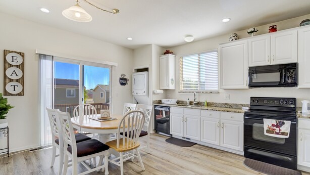 A kitchen with white cabinets, a dining table with chairs, a refrigerator, a microwave, and an oven.