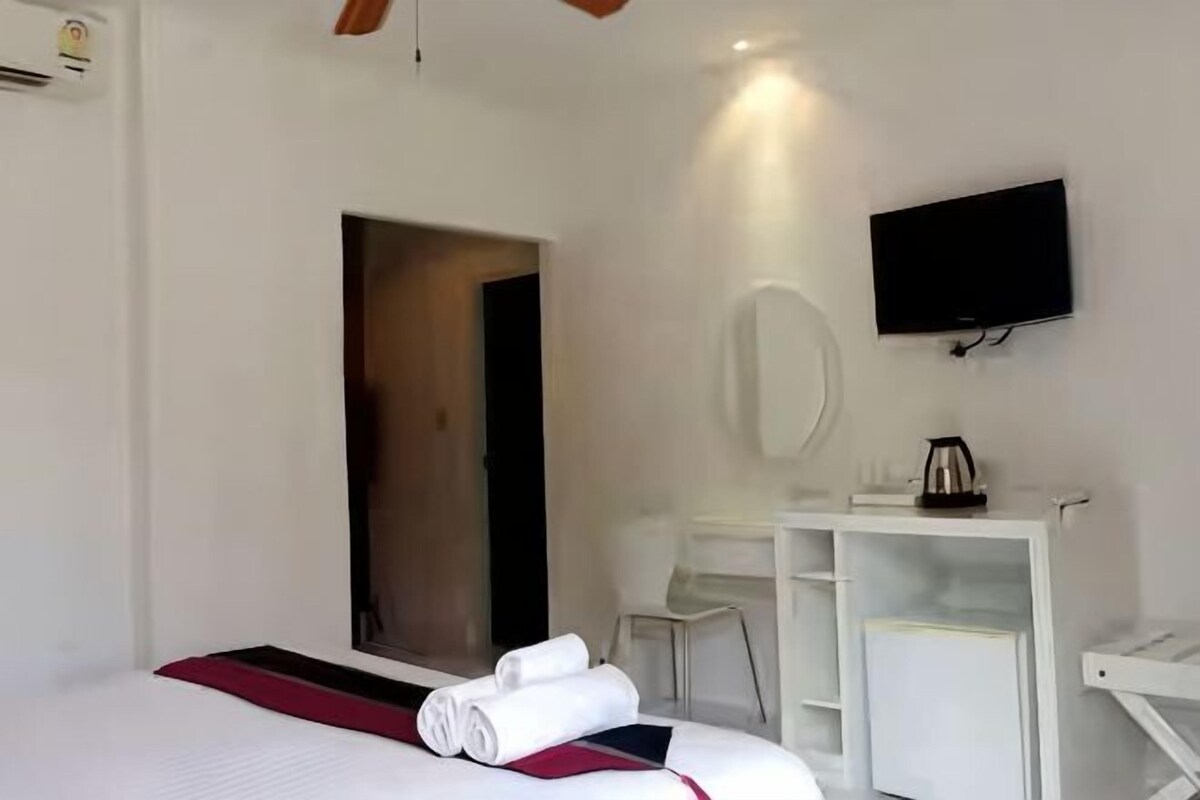 A hotel room with a bed, a desk, a chair, a television, and a mirror.