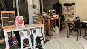 A coffee shop interior with a chalkboard menu, a coffee sign, and a counter with stools. - Kata Lovely Rest Bed and Breakfast (Phuket)