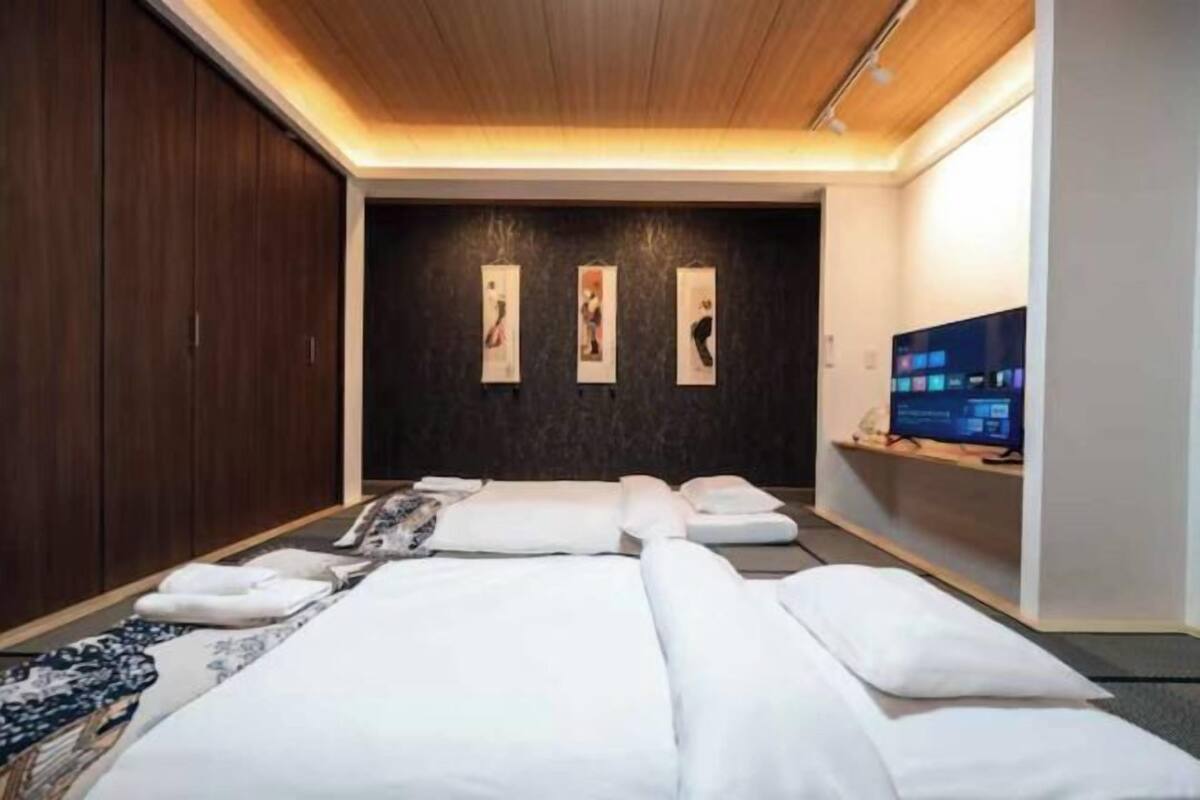 A hotel room with a bed, a TV, and artwork on the wall.