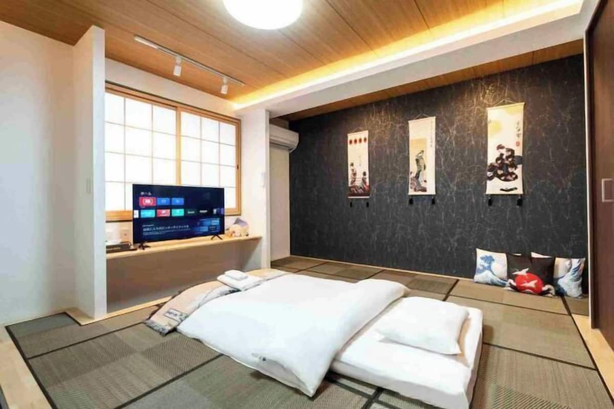 A modern hotel room with a bed, a TV, and artwork on the wall.