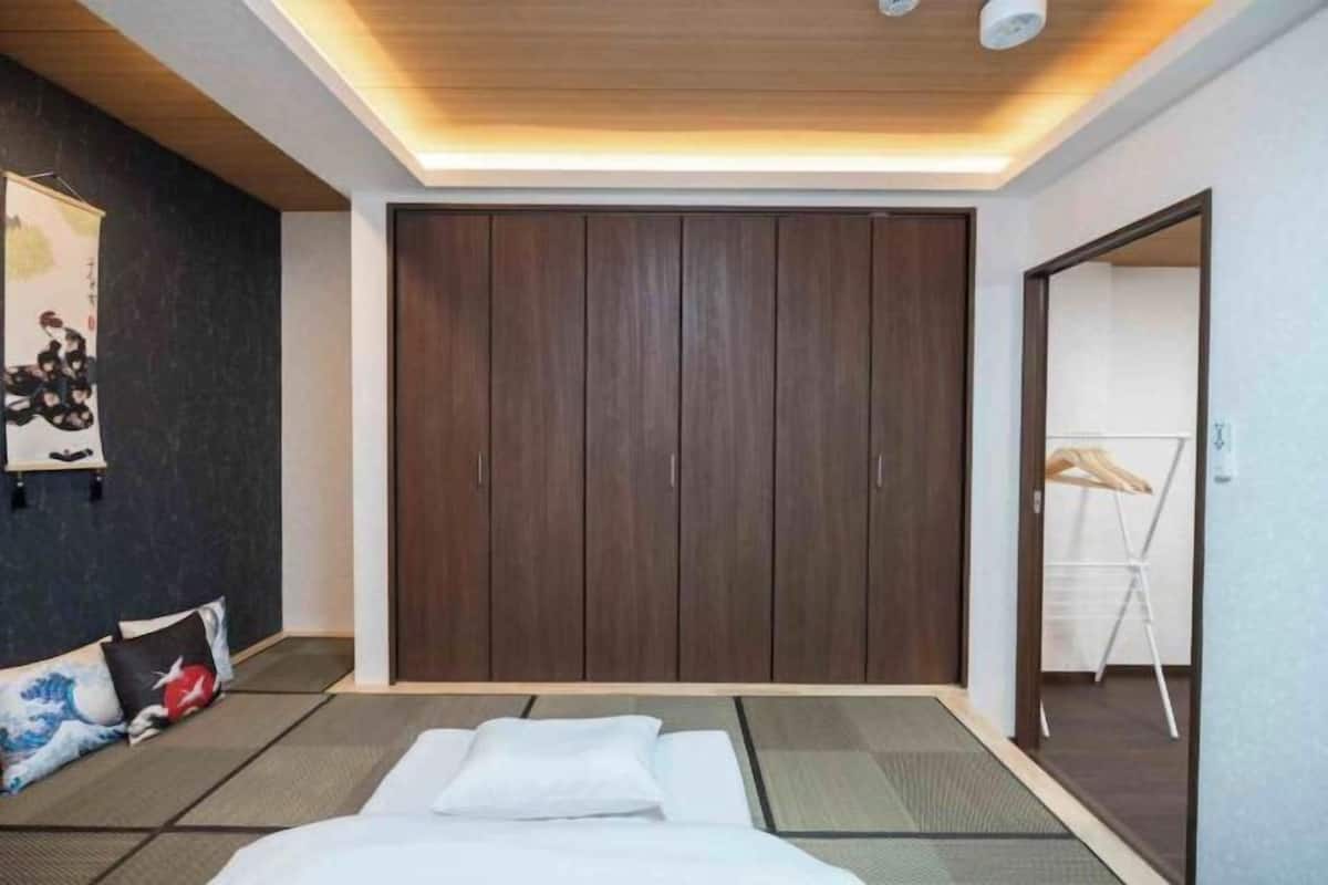 A hotel room with a bed, a wardrobe, a wall-mounted artwork, and a mirror.