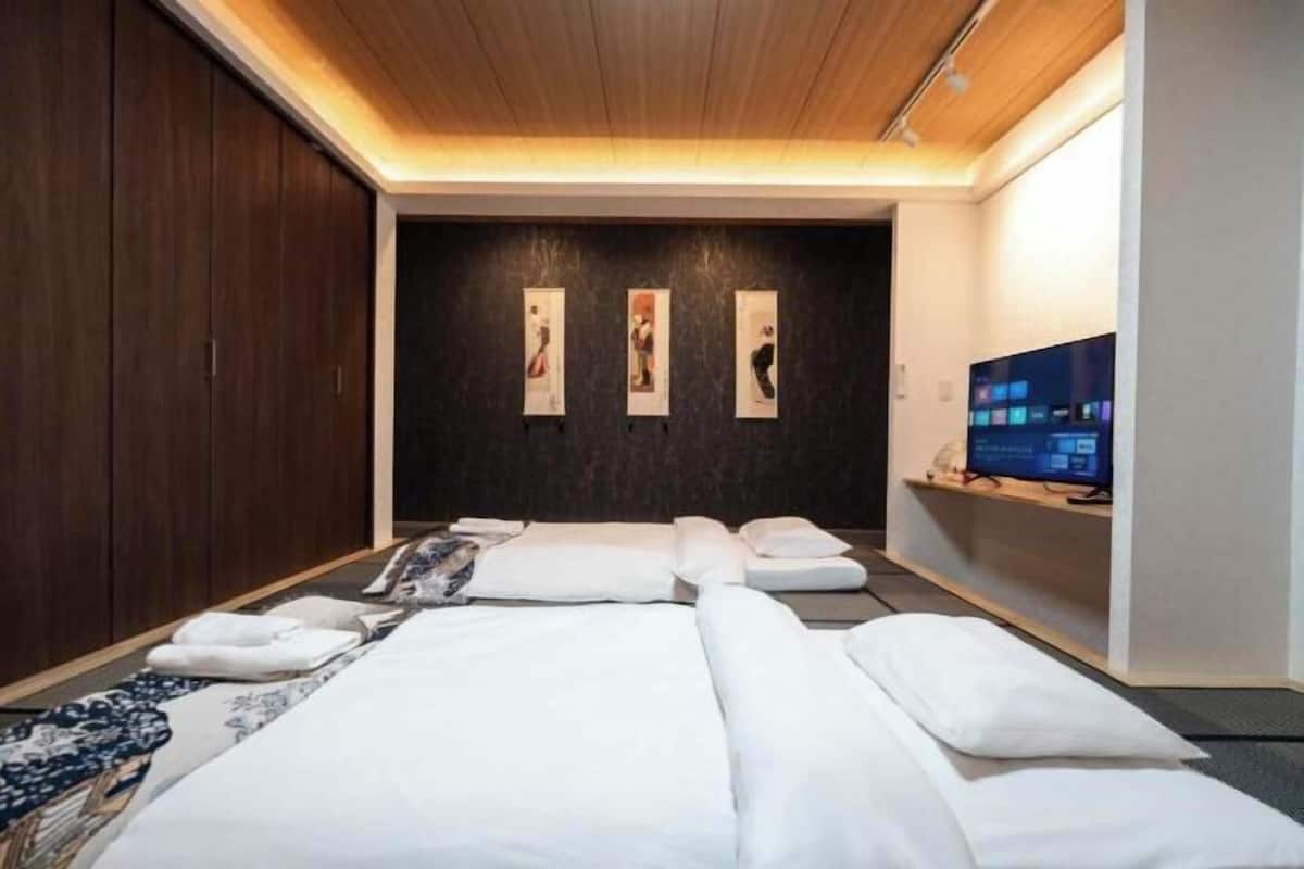 A hotel room with a bed, a TV, and artwork on the wall.