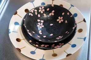 A black bowl with pink floral patterns on a white plate with blue and brown designs. - OHAYO Ryogoku (Tokyo)