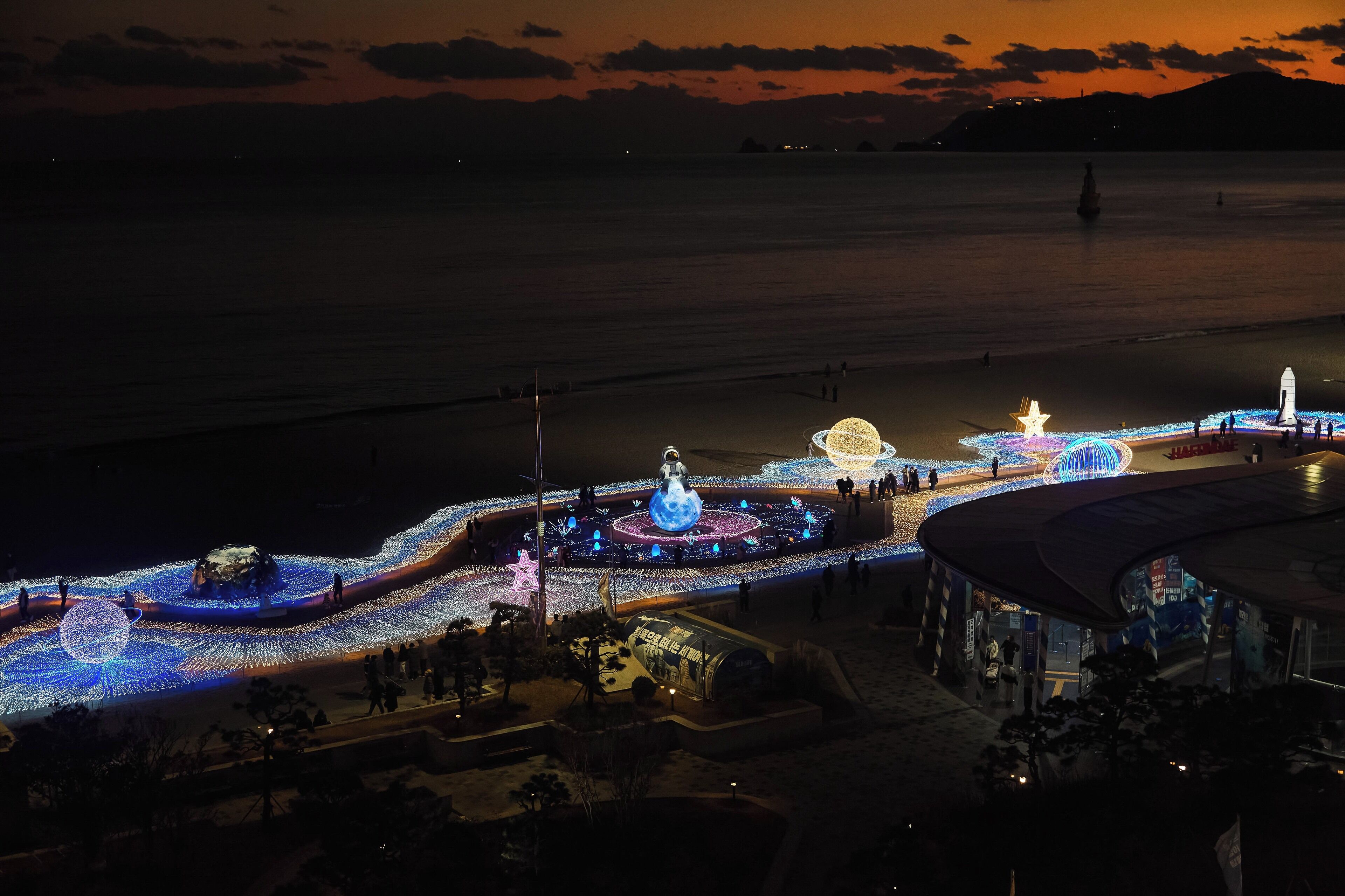 A waterfront promenade with illuminated structures and a clear view of the sea.