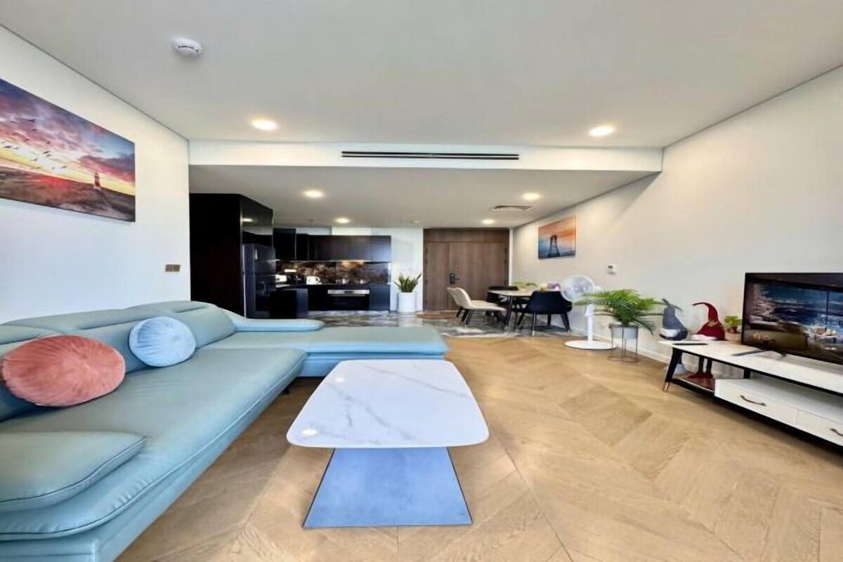 A modern living room with a sectional sofa, a marble coffee table, and a TV.
