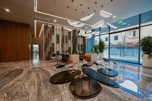 A modern lobby with a marble floor, contemporary furniture, and large windows offering views. - Lumiere Riverside - Best Luxury Condo Design D2 (Ho Chi Minh City)