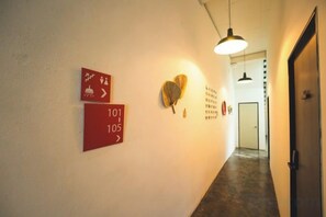 A hallway with directional signs, a hanging fan, and a door at the end. - Carnarvon 73 (George Town)