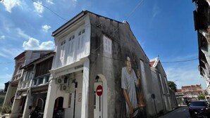 A building with a mural of a person on the side. - Carnarvon 73 (George Town)