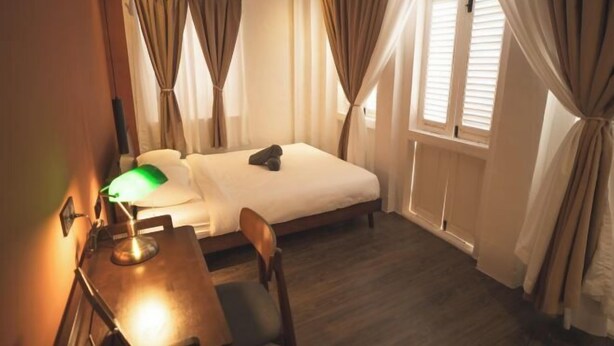 A bedroom with a bed, a desk with a lamp, curtains, and a window. - Carnarvon 73 (George Town)