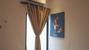A room with an air conditioning unit, a window with beige curtains, and a framed picture on the wall. - Carnarvon 73 (George Town)