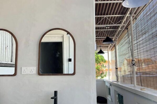 A room with a white wall, a door, and a window with a metal grid. - Carnarvon 73 (George Town)