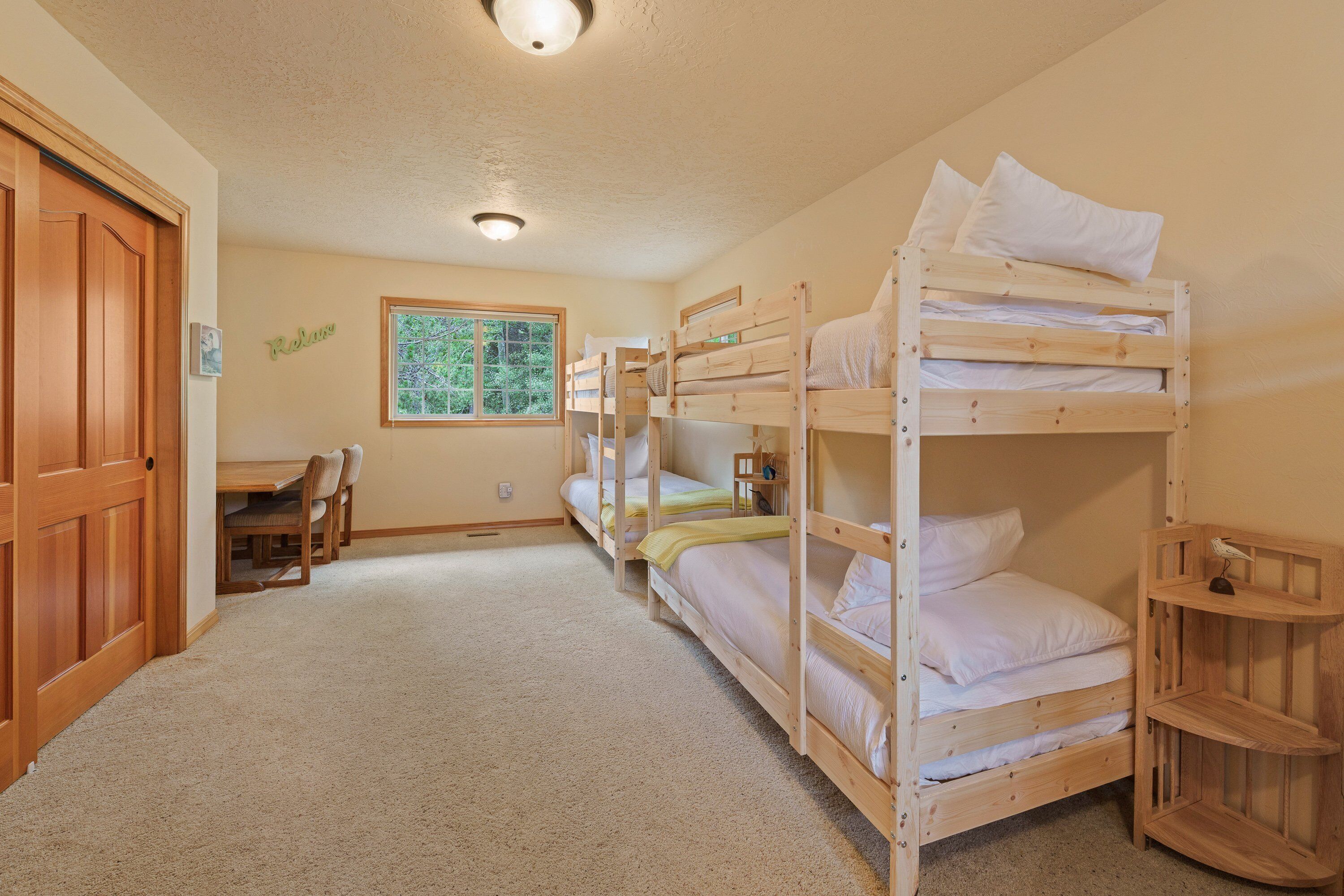 A room with bunk beds, a desk, and a window.
