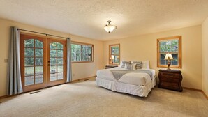 A bedroom with a large bed, a nightstand, a lamp, and a ceiling fan. - 4 Tan Oak - Sunriver Family Oasis, Fireplace, BBQ, Patio & Private Hot Tub (Bend)