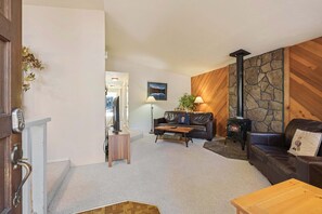 A cozy living room with a fireplace, leather sofas, a coffee table, and a stone wall. - Timber 12 - Cabin, SHARC Passes + Walkable, Private Hot Tub (Sunriver)