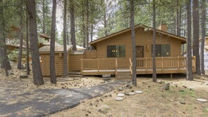 A cabin with a porch, surrounded by trees. - Timber 12 - Cabin, SHARC Passes + Walkable, Private Hot Tub (Sunriver)