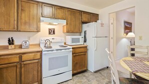 A kitchen with wooden cabinets, a stove, a microwave, and a refrigerator.