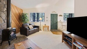 A cozy living room with a fireplace, a sofa, a coffee table, and a television.