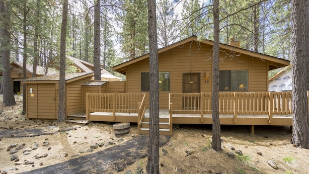 A cabin with a porch, wooden deck, and a small shed. - Timber 12 - Cabin, SHARC Passes + Walkable, Private Hot Tub (Sunriver)