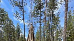 An outdoor patio with a round table, chairs, and an umbrella. - Trapper 11 - A-Frame, Wood Stove, Pool Table (Sunriver)