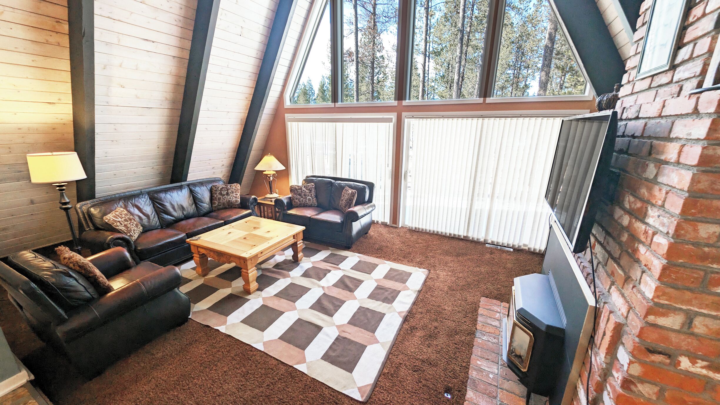 A cozy living room with a fireplace, two sofas, a coffee table, and a patterned rug.