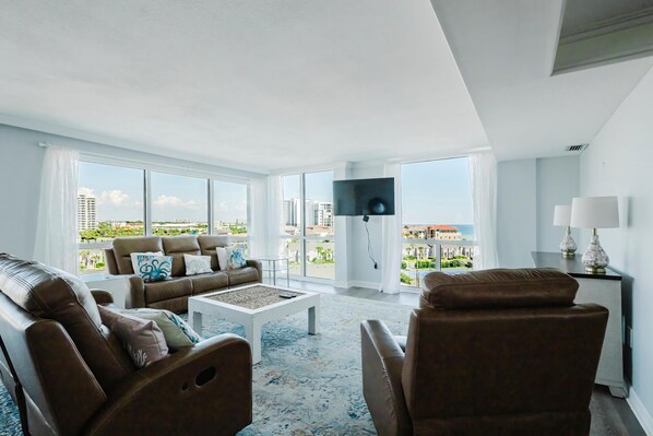 A spacious living room with a large window, a flat-screen TV, and a view of the cityscape.